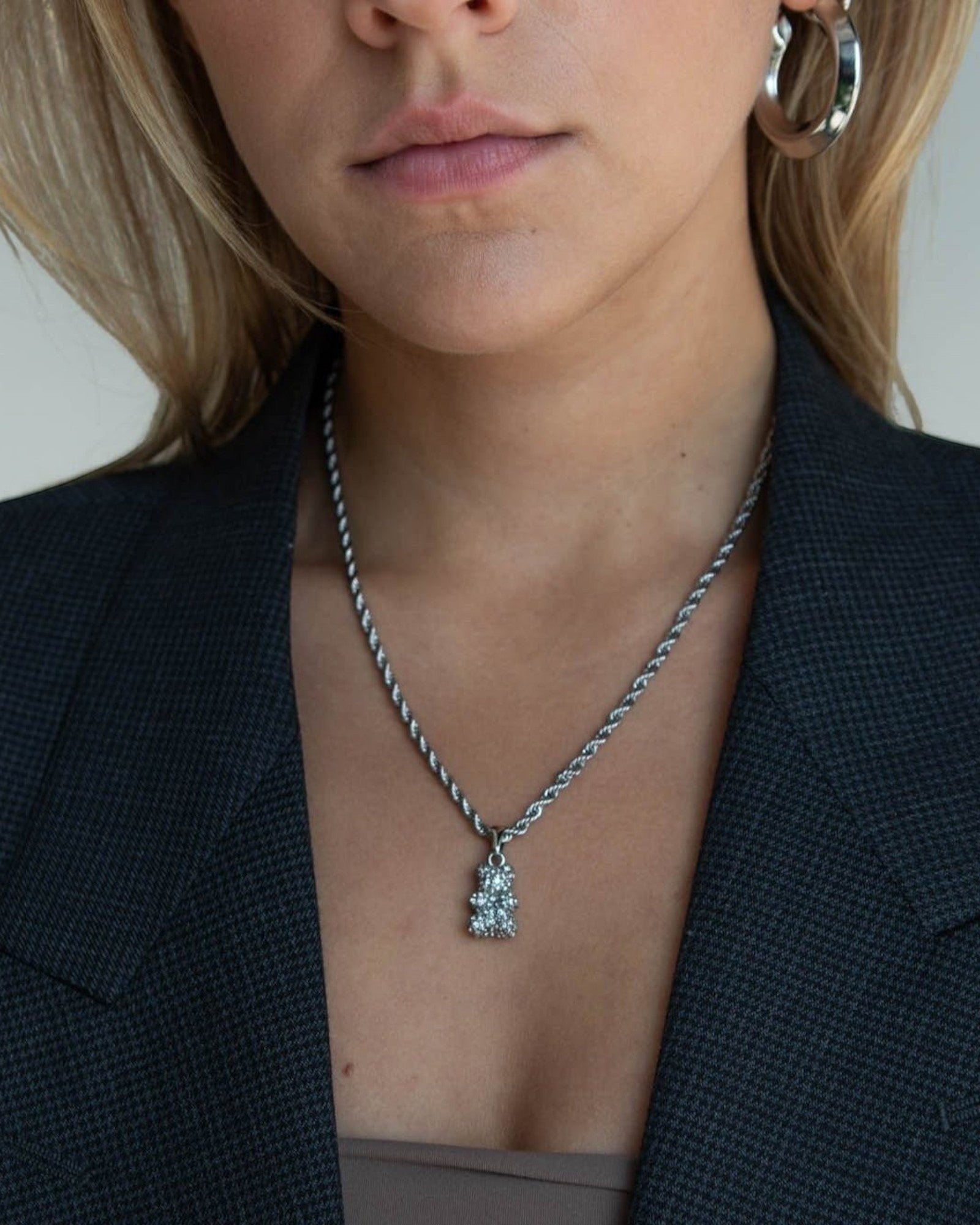 Réalta silver-tone pavé bear pendant on a delicate rope chain worn by a woman in a dark blazer