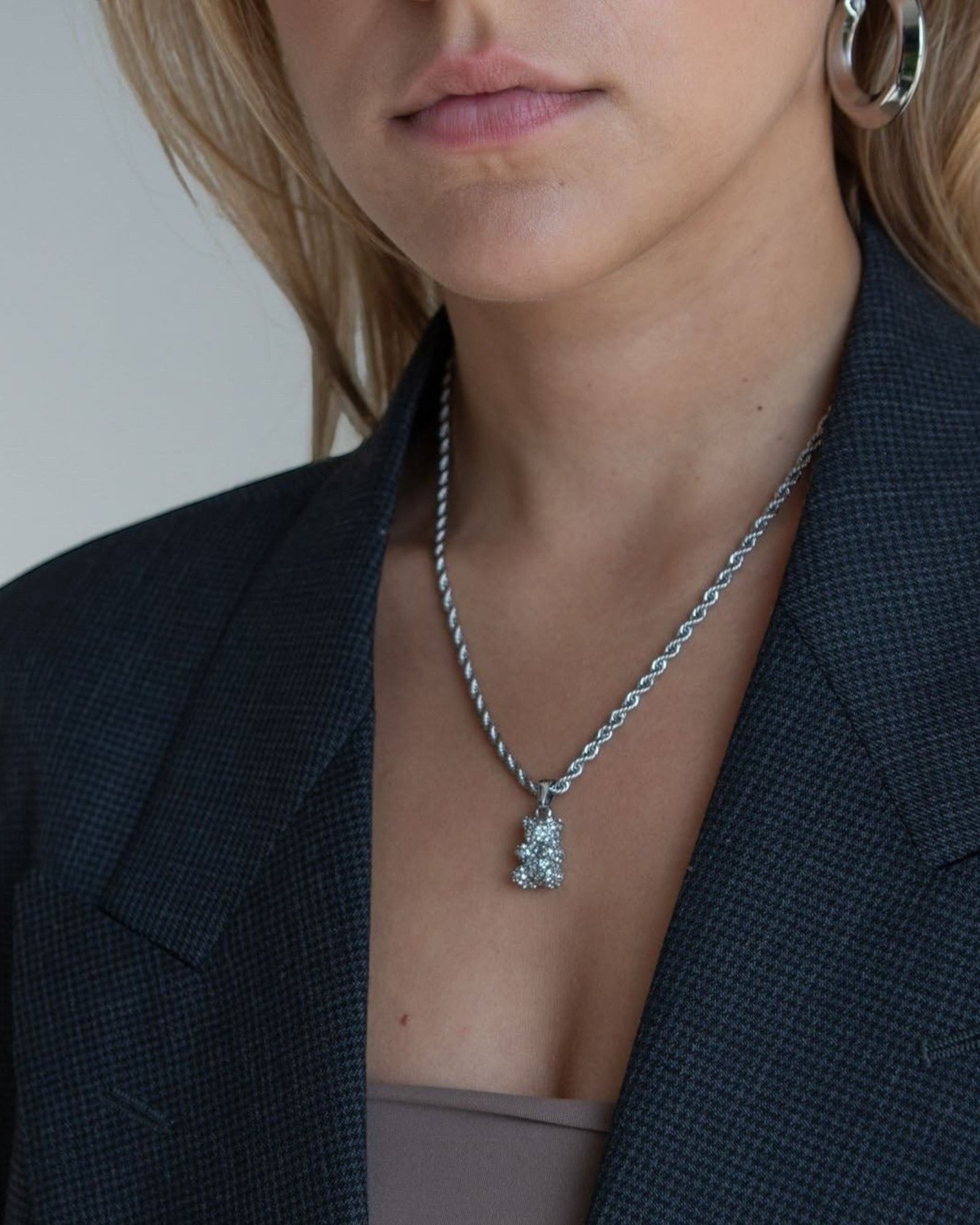 Réalta silver pavé bear pendant necklace on a rope chain worn by a woman in a charcoal blazer